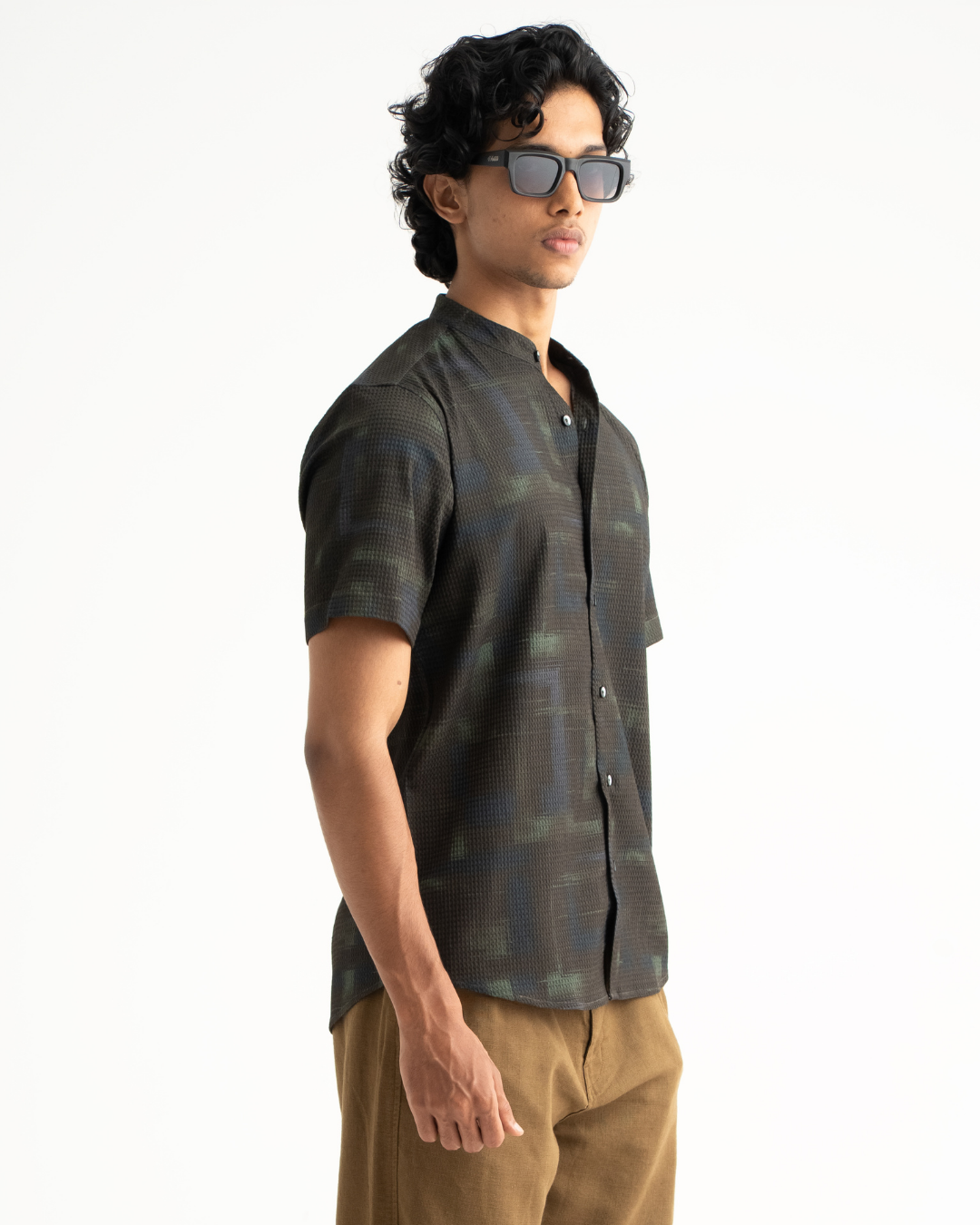 Man wearing a patterned shirt and sunglasses on a white background